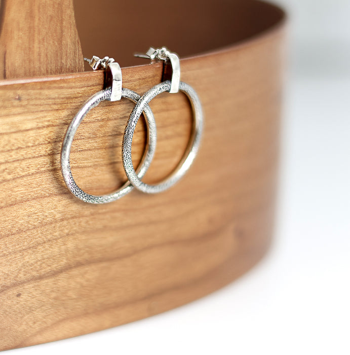 Silver hoop earrings on a wooden surface