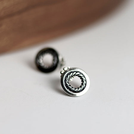 Silver earrings with circular design on a light surface