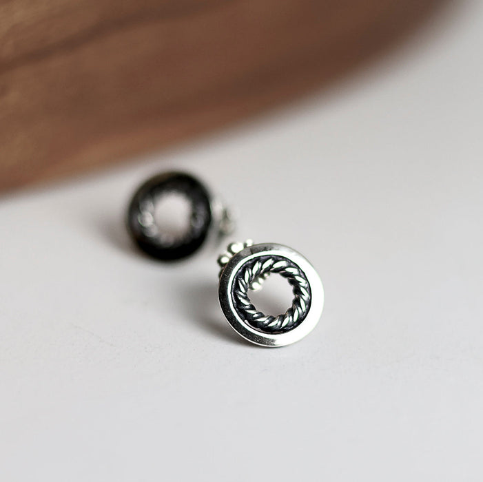 Silver earrings with circular design on a light surface