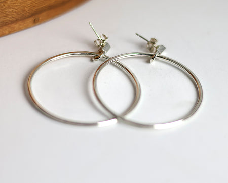 Silver hoop earrings on a white surface