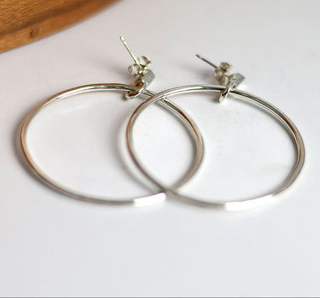 Silver hoop earrings on a white surface