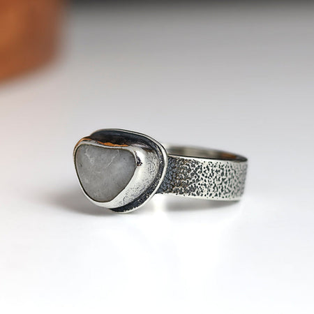 Silver ring with a heart-shaped stone on a white background