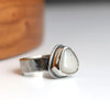 Silver ring with a white stone on a light background