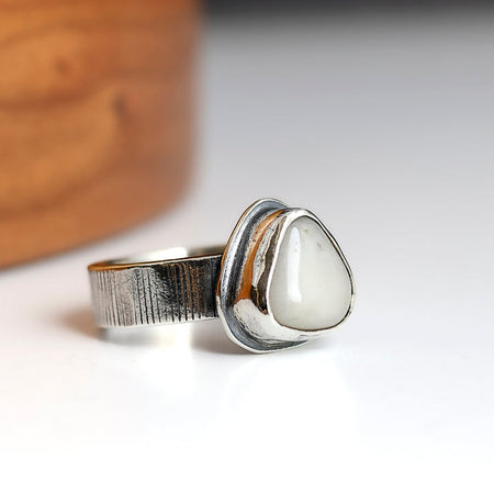 Silver ring with a white stone on a light background