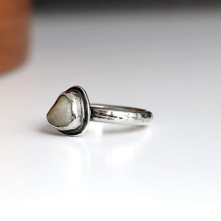 Silver ring with a white beach stone on a white background