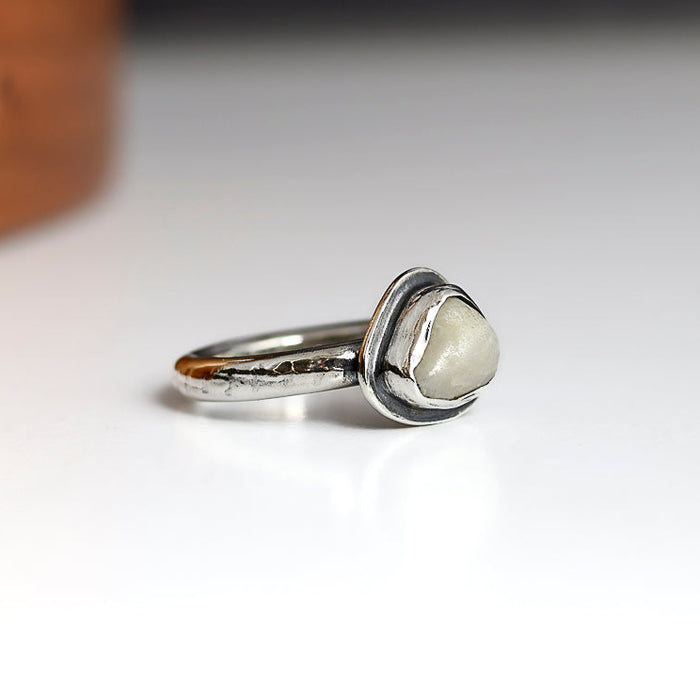 Silver ring with a beach stone on a white background