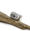 Silver ring with a multicolored stone on a wooden branch