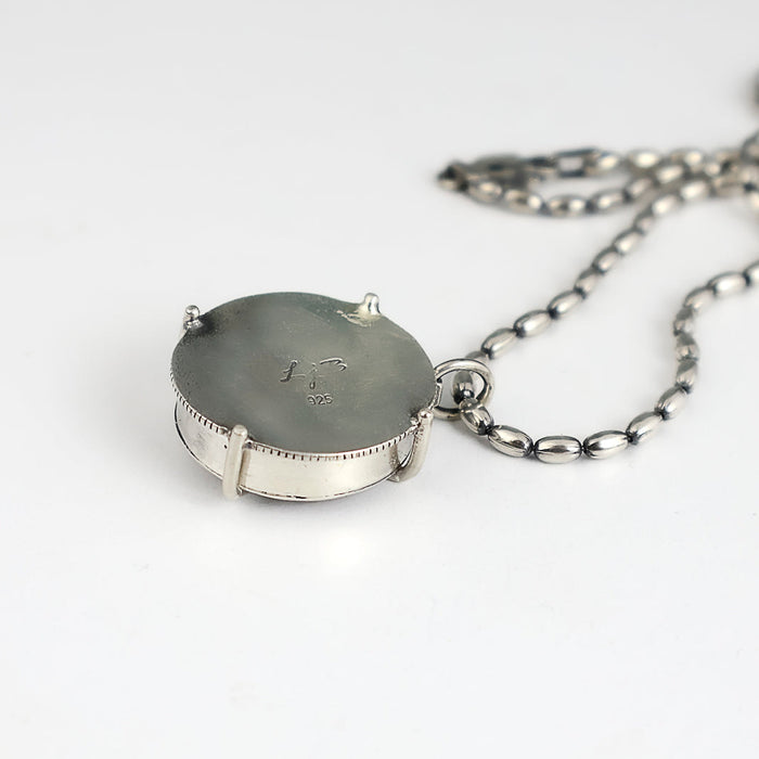 the back view of an amethyst pendant on an oval silver bead chain