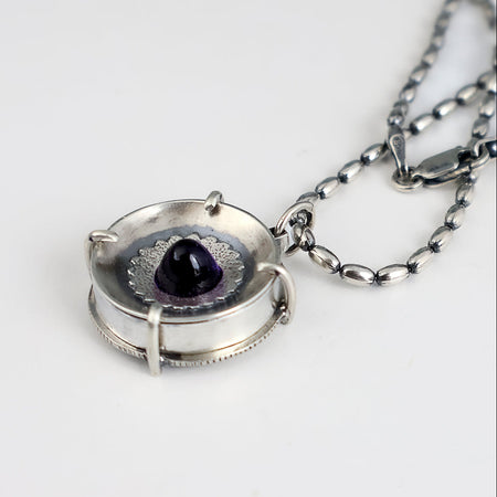 Handmade sterling silver pendant with high dome amethyst in a sand textured flower frame inside a pronged silver cup, on an oval bead chain