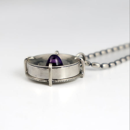 Handmade sterling silver pendant with high dome amethyst in a sand textured flower frame inside a pronged silver cup, on an oval bead chain
