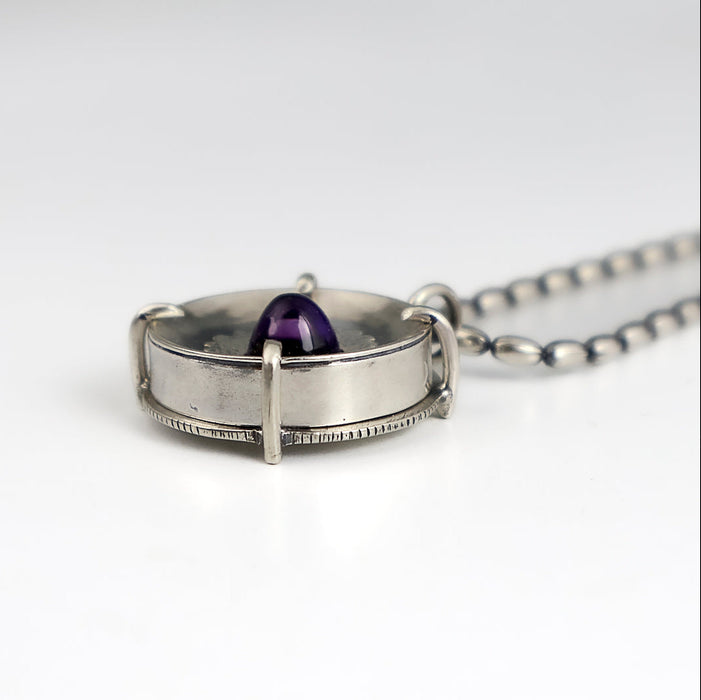 Handmade sterling silver pendant with high dome amethyst in a sand textured flower frame inside a pronged silver cup, on an oval bead chain