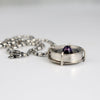 Handmade sterling silver pendant with high dome amethyst in a sand textured flower frame inside a pronged silver cup, on an oval bead chain