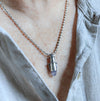 Handmade sterling silver tube pendant  worn on a person with riveted nesting tubes holding a lavender blue chalcedony point, oxidized patina, on an oval bead chain
