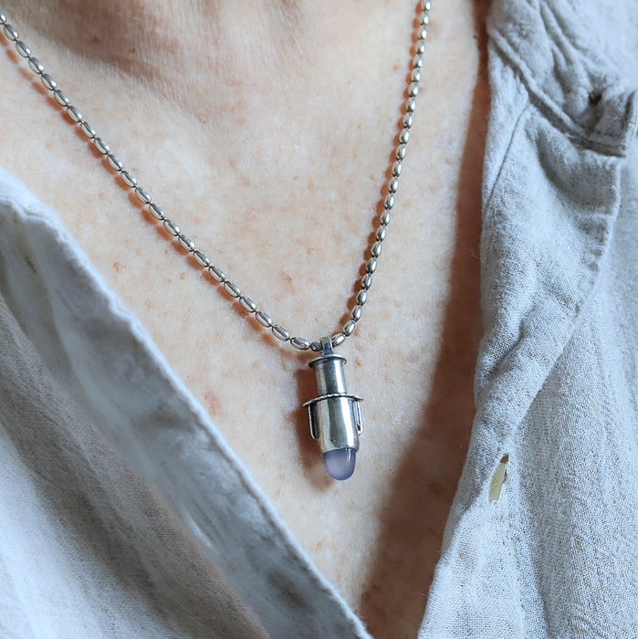 Handmade sterling silver tube pendant  worn on a person with riveted nesting tubes holding a lavender blue chalcedony point, oxidized patina, on an oval bead chain