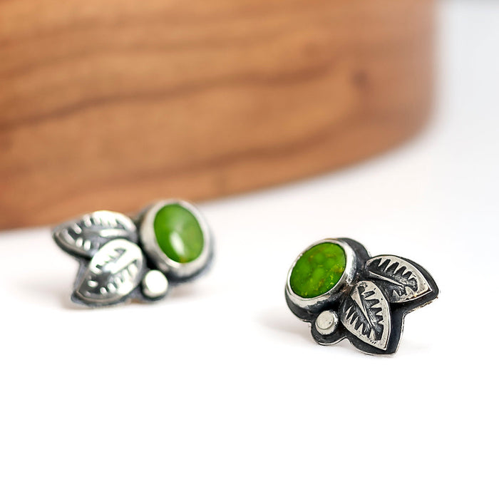Silver leaf-shaped earrings with a green turquoise on a white background