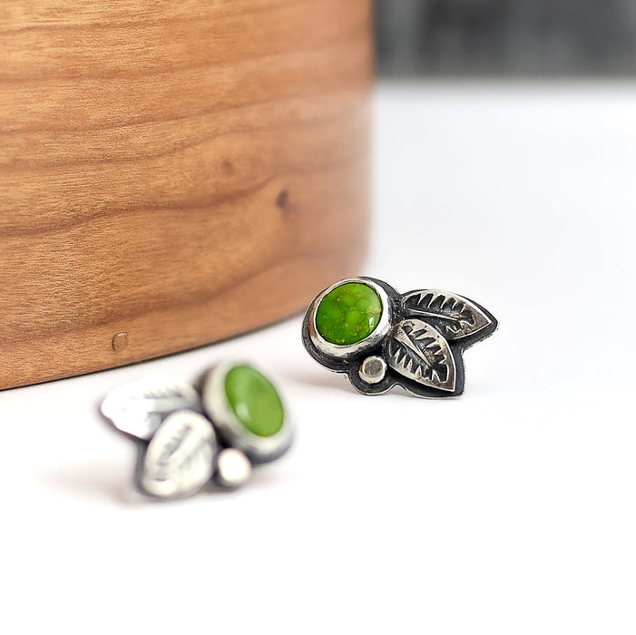 Silver leaf-shaped earrings with a green turquoise on a white background