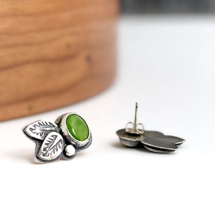 Silver leaf-shaped earrings with a green turquoise on a white background