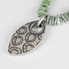 Necklace with a silver pendant and turquoise beads on a light gray background