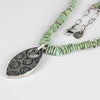 Necklace with green turquoise  beads and a silver pendant on a white background 