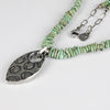 Necklace with green turquoise beaded chain and silver pendant on a white background