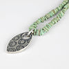 Necklace with green turquoise beaded necklace and silver pendant on a white background