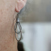 Close-up of a silver earring worn on an ear with a blurred background