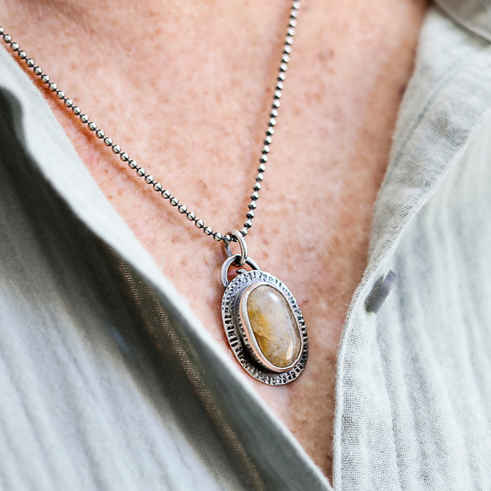 Necklace with a pendant worn by a person, focusing on the jewelry.
