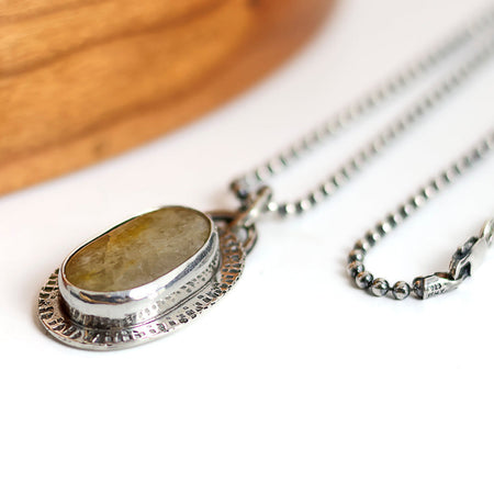 Silver necklace with a pendant on a white surface