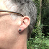 small silver stud earrings on ear