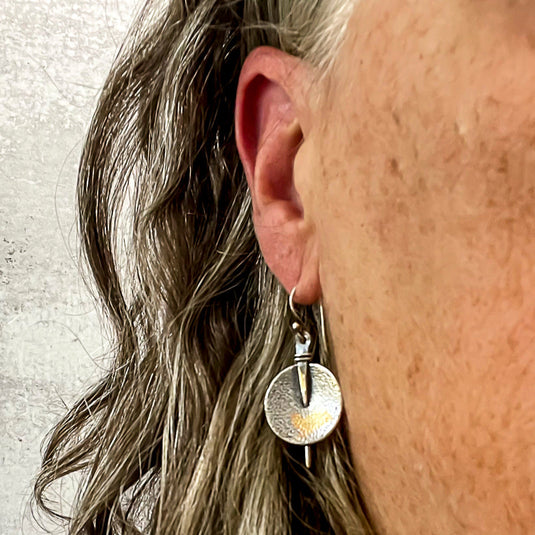 silver dangle earrings on ear